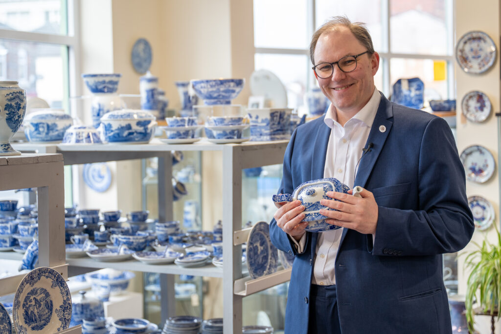 Gareth Snell MP holding a ceramic jug with more plates and jugs on display behind him.