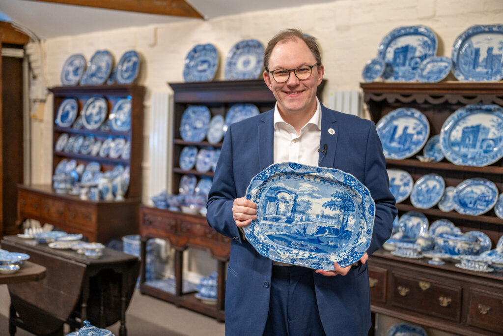 Gareth Snell MP holding a ceramic plate with more plates in the background on show.