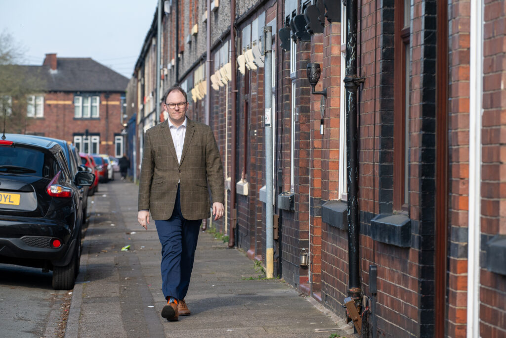 Gareth Snell MP walking down a pavement of terraced houses in Stoke-on-Trent.