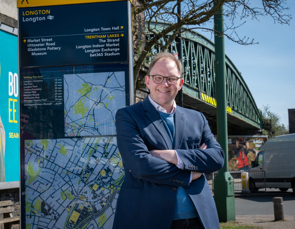 Gareth Snell MP stood with his arms crossed in front of the public transport sign in Longton, Stoke-on-Trent