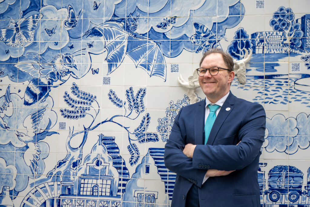 Gareth Snell MP stood with his arms crossed and smiling in front of the ceramic display wall.